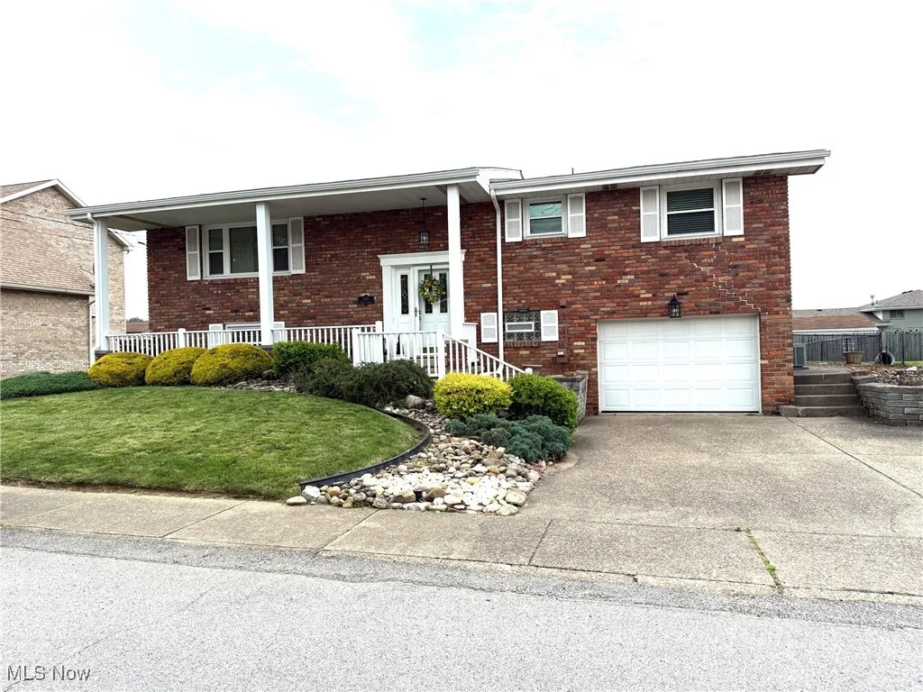 Front of home featuring brick siding, driveway, an attached garage, and a porch