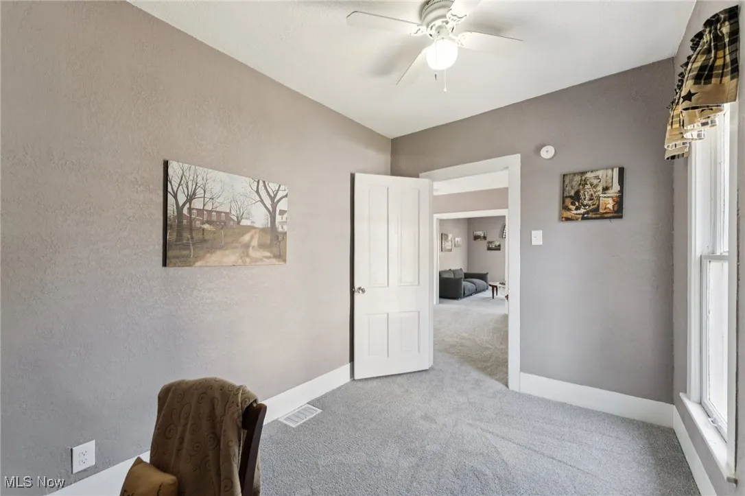 Office space featuring carpet flooring, a ceiling fan, and a textured wall