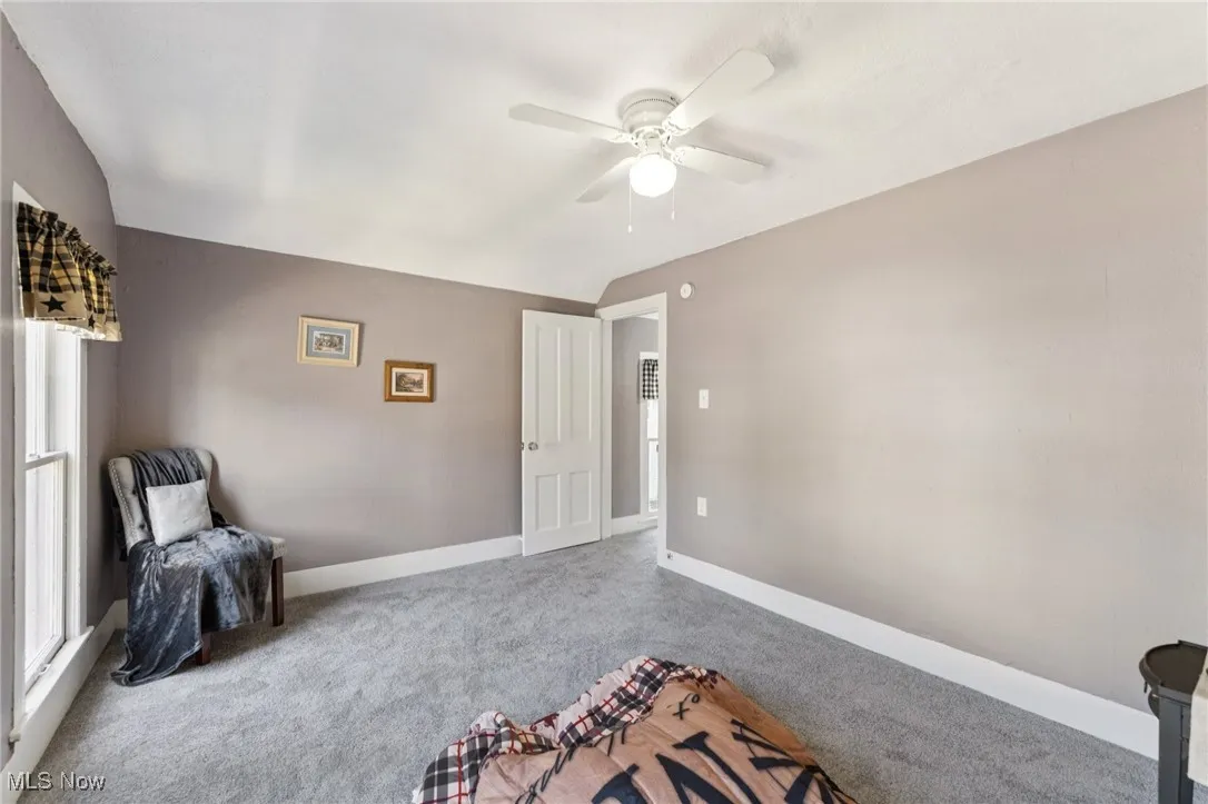 Sitting room featuring carpet, ceiling fan, and vaulted ceiling