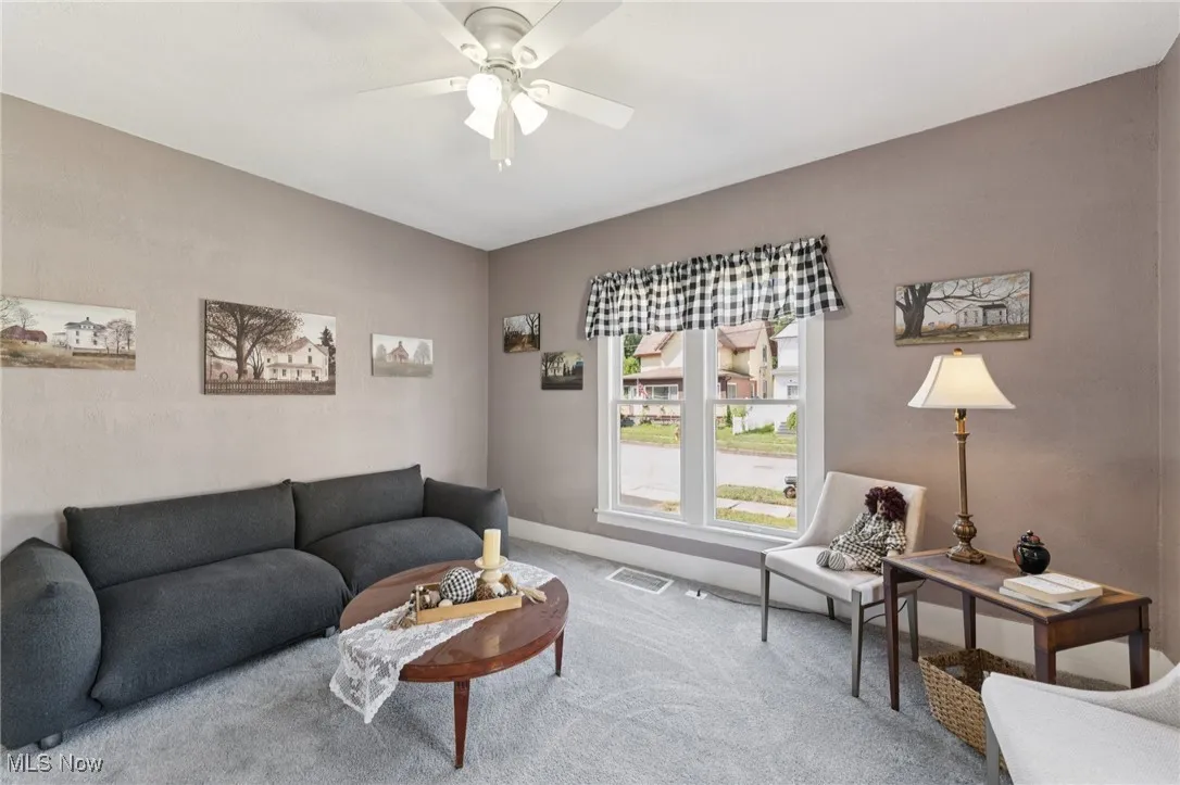 Carpeted living area with a ceiling fan and lofted ceiling