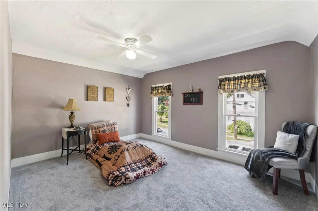 Sitting room featuring ceiling fan, carpet flooring, and vaulted ceiling