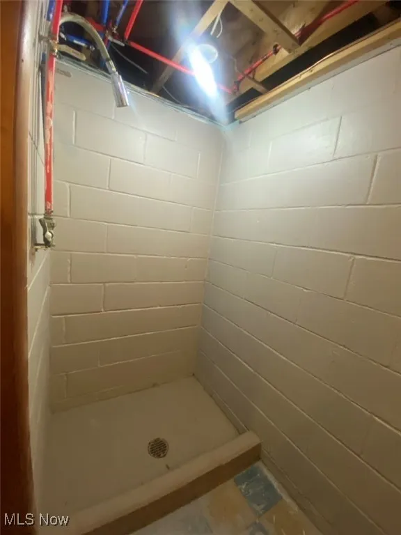 Bathroom with a tile shower and concrete block wall