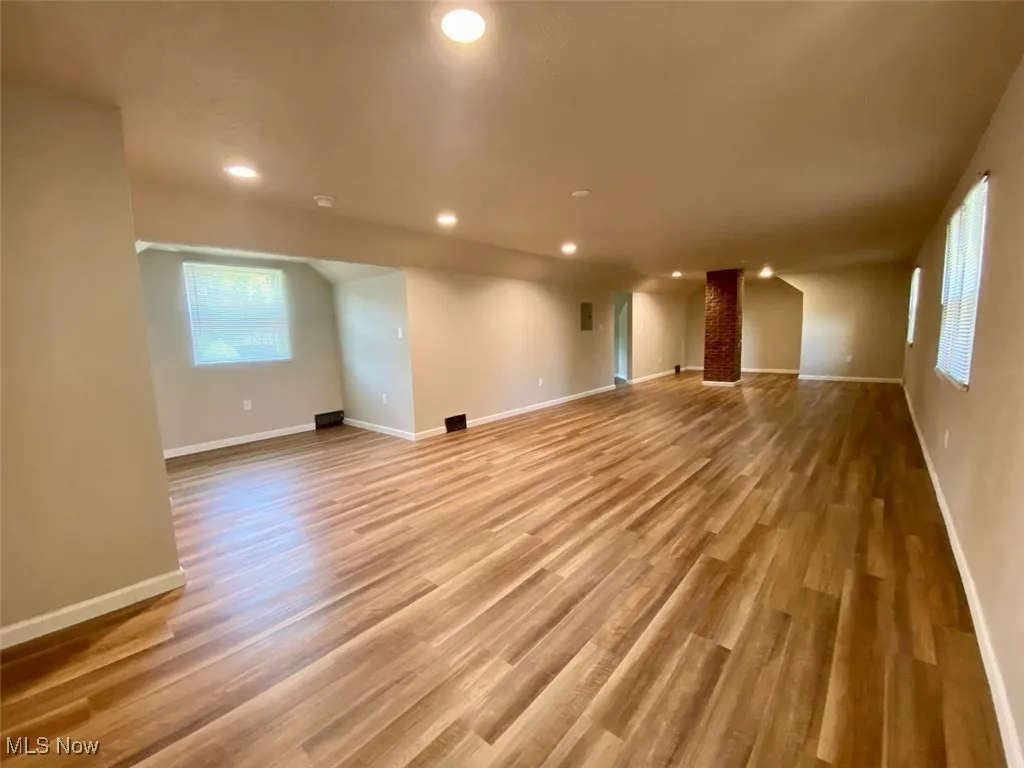 Unfurnished living room with wood finished floors, recessed lighting, and lofted ceiling