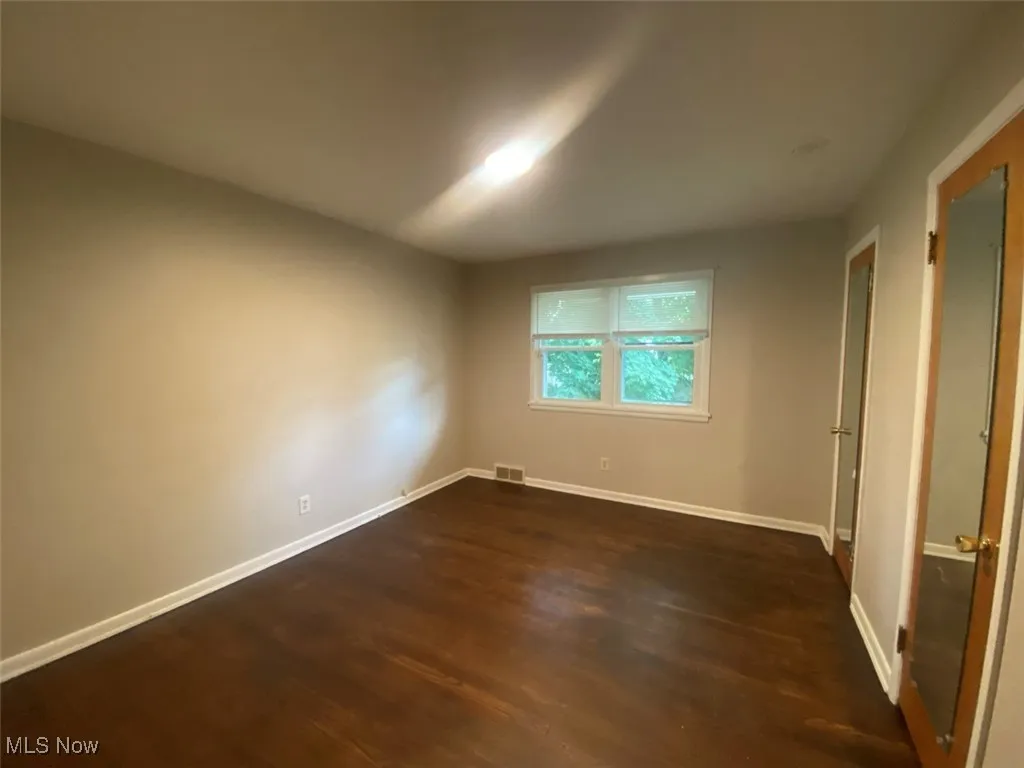 Unfurnished bedroom featuring dark wood-style flooring and baseboards