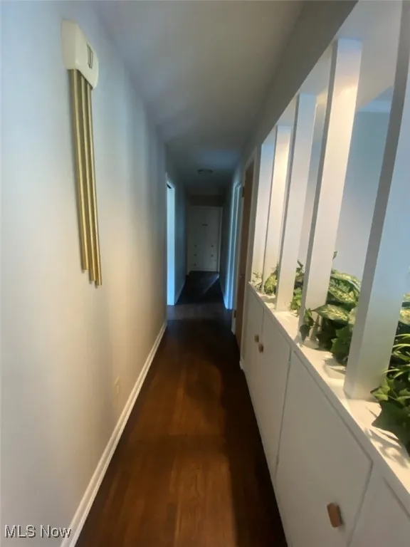 Corridor featuring dark wood finished floors and baseboards