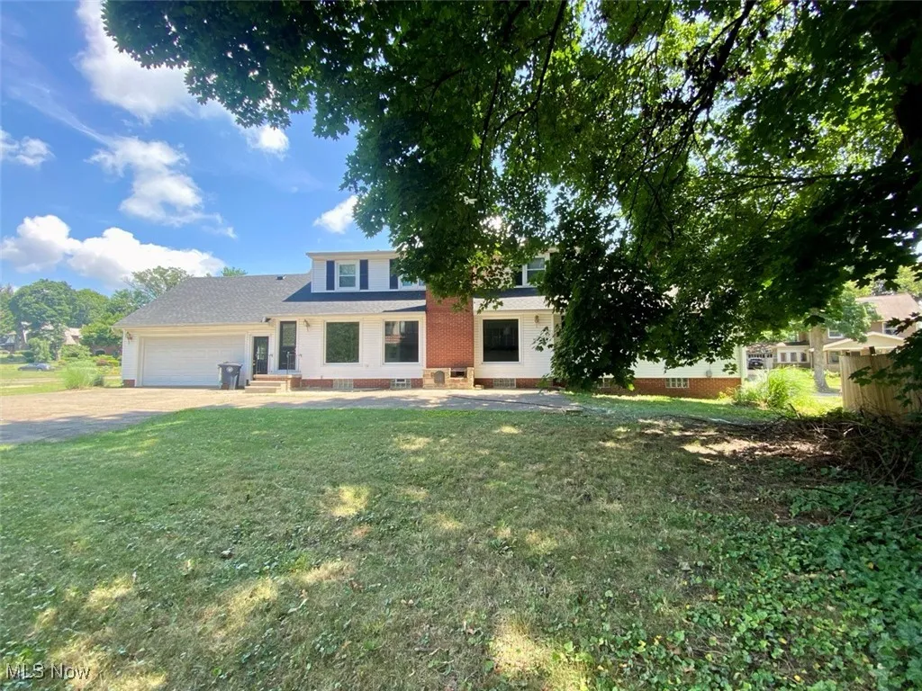 View of front of property featuring an attached garage, a front lawn, and driveway