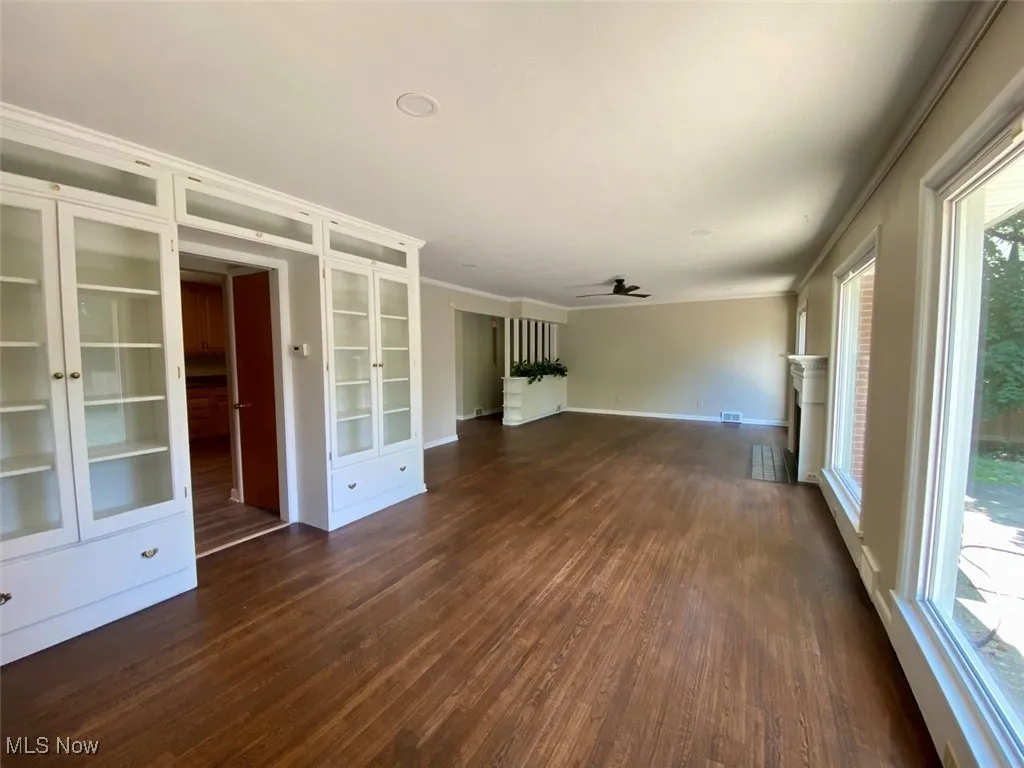 Empty room featuring french doors, dark wood-type flooring, crown molding, ceiling fan, and built in shelves