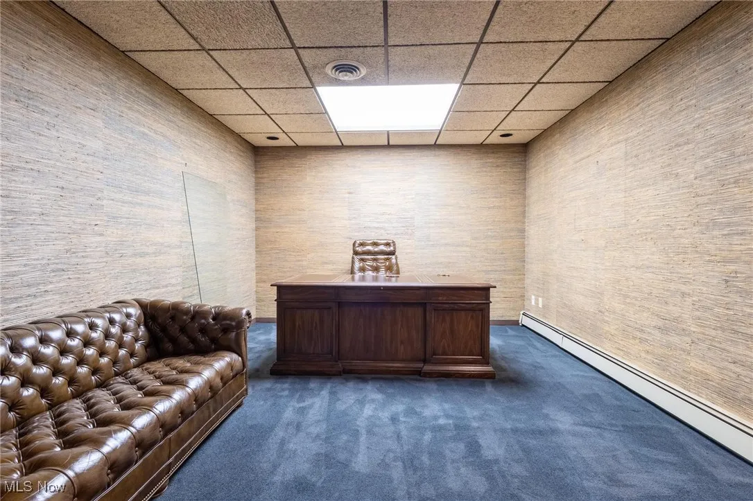 Home office featuring dark carpet, a baseboard heating unit, and a drop ceiling