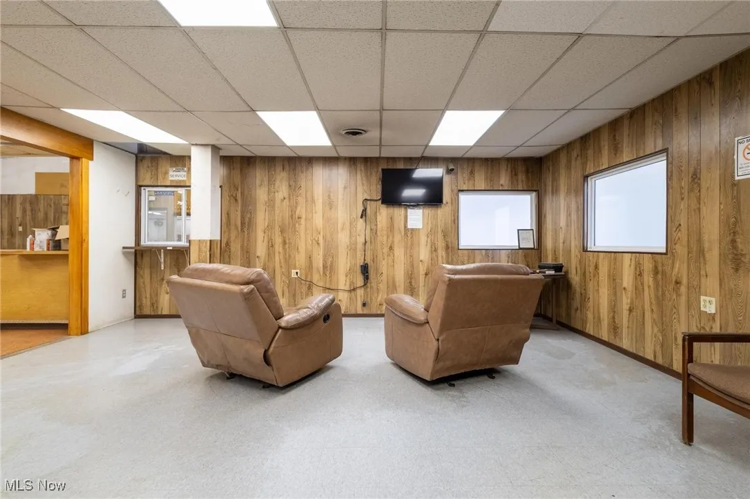 Living room featuring wood walls and a paneled ceiling
