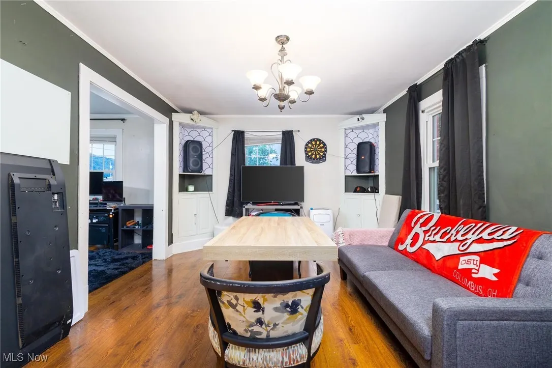 Living room featuring a chandelier, wood finished floors, and ornamental molding