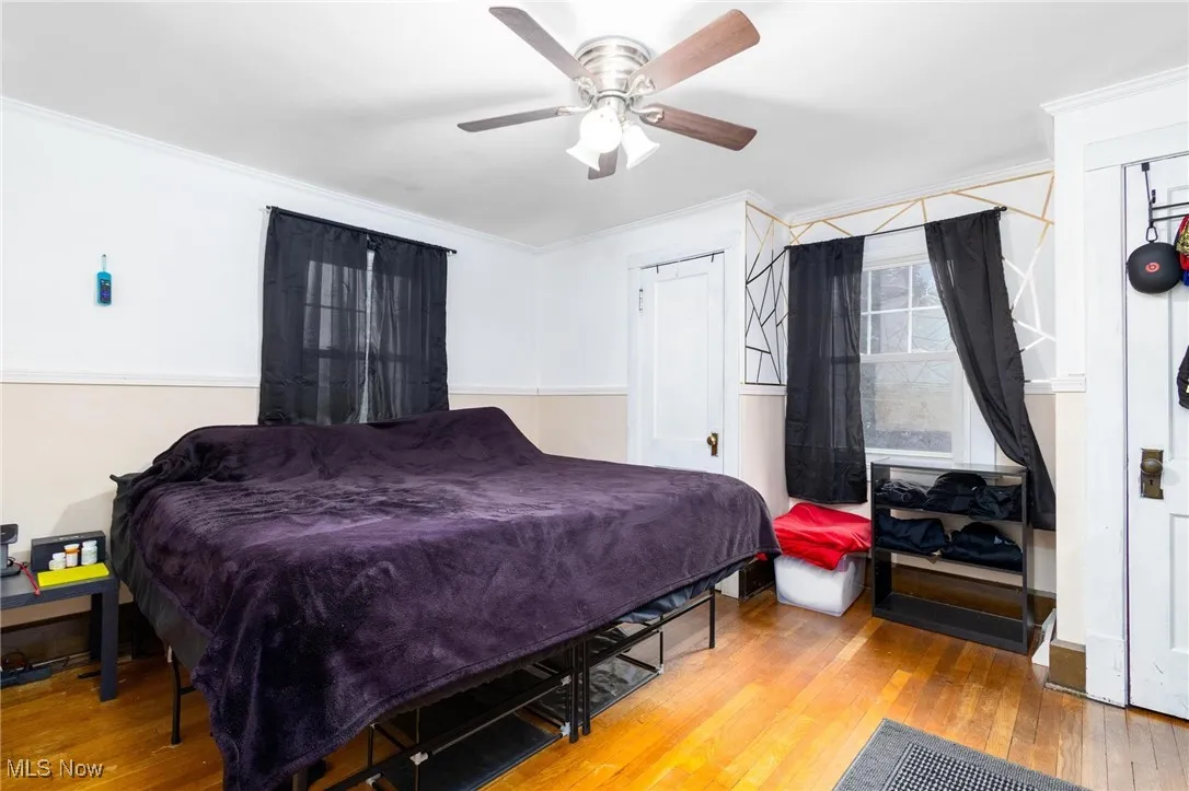 Bedroom with wood-type flooring, crown molding, and ceiling fan