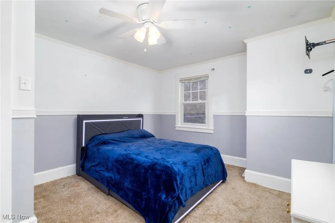 Carpeted bedroom with ornamental molding and ceiling fan