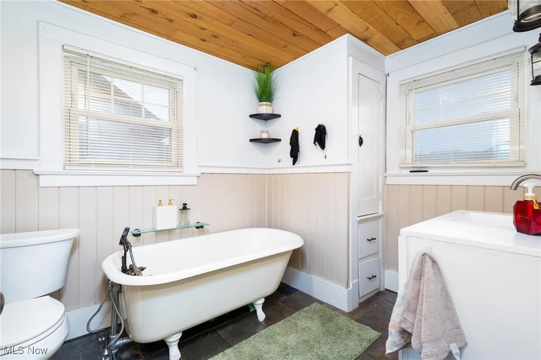 Full bath featuring a wainscoted wall, a freestanding bath, and wood ceiling