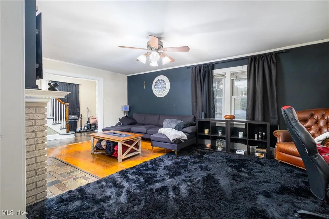 Living room with ceiling fan and stairway