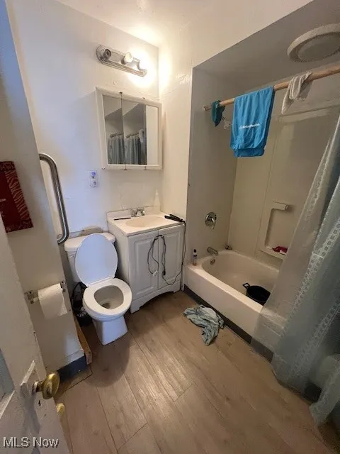 Bathroom featuring wood finished floors, vanity, and shower / bath combo with shower curtain