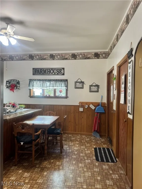Dining area with a wainscoted wall, a ceiling fan, brick patterned floors, and wooden walls