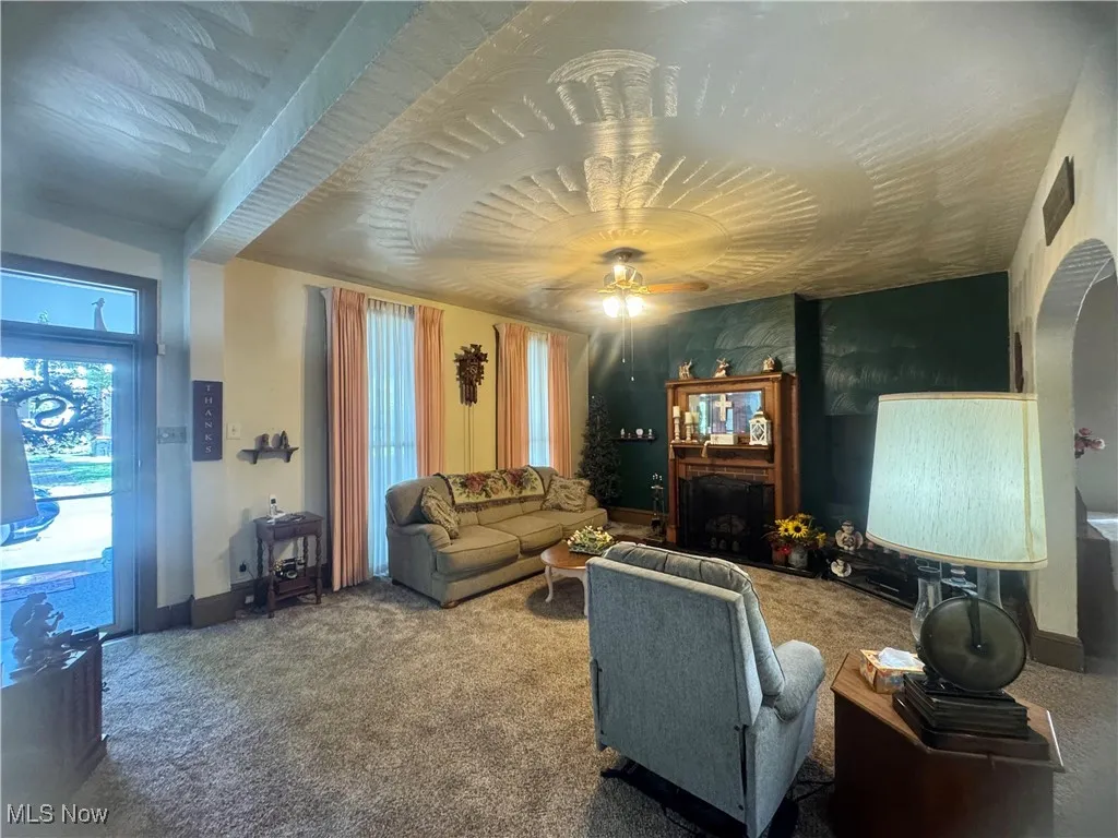 Carpeted living room with a fireplace and ceiling fan