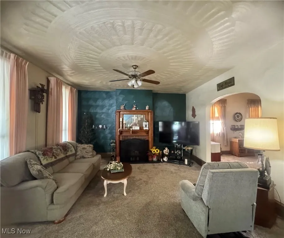 Carpeted living area with arched walkways and ceiling​​‌​​​​‌​​‌‌​‌‌​​​‌‌​‌​‌​‌​​​‌​​ fan