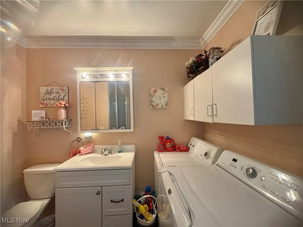 Laundry area featuring separate washer and dryer and ornamental molding