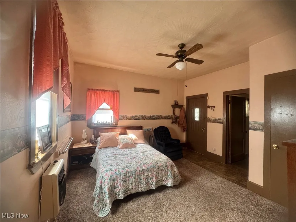 Carpeted bedroom with a ceiling fan