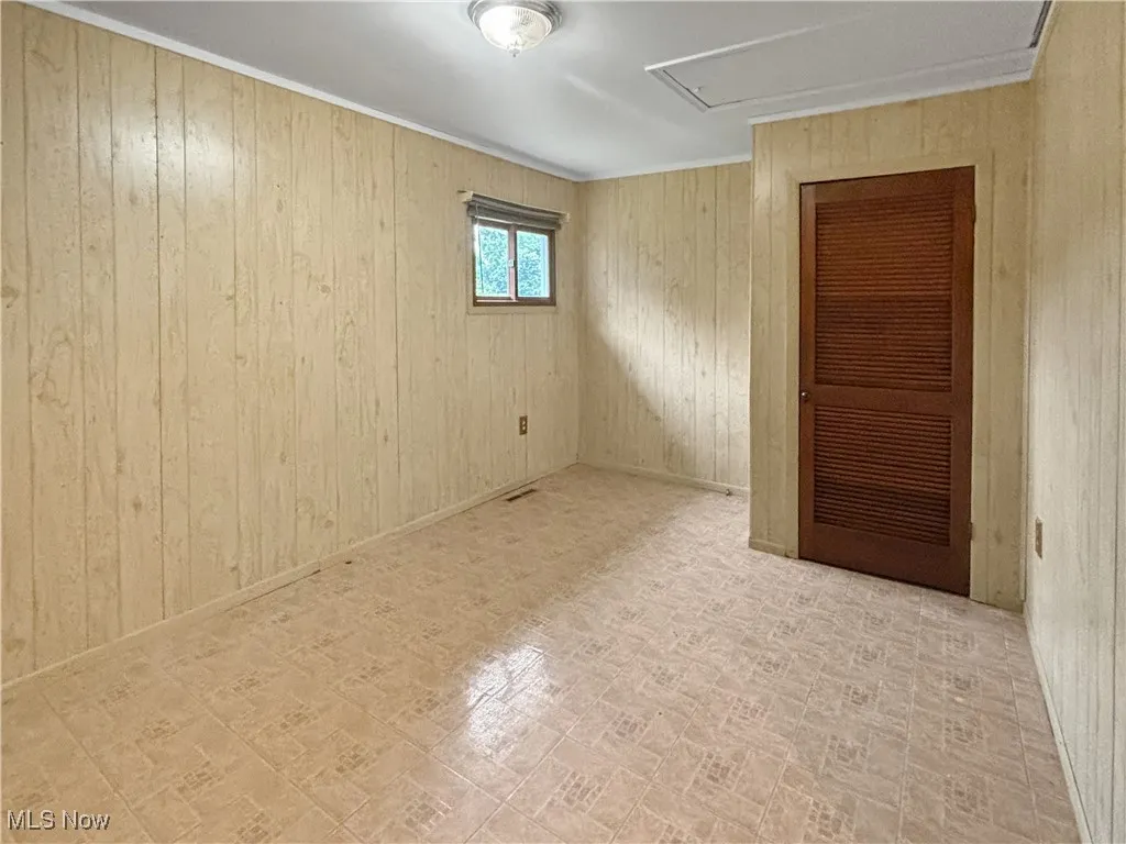 Unfurnished room with wooden walls and brick patterned floors