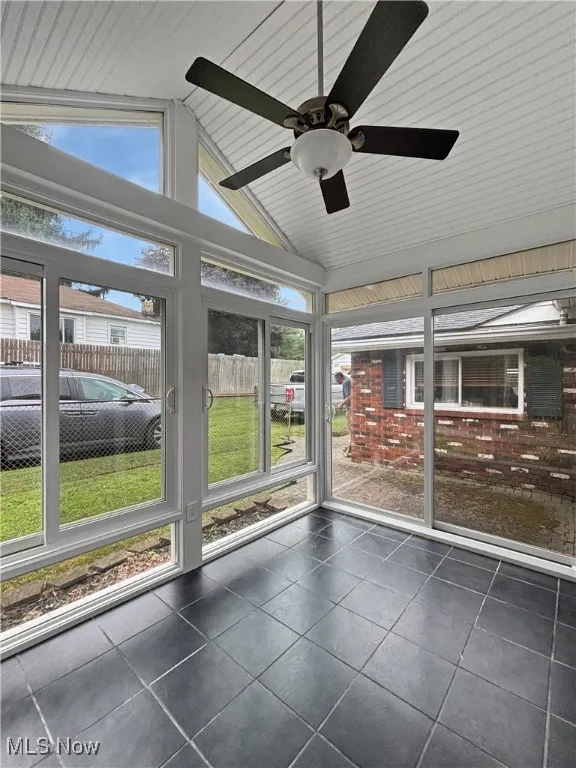 Unfurnished sunroom with vaulted ceiling and a ceiling fan