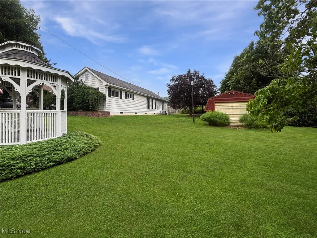 View of green lawn featuring a gazebo, a garage, and an outbuilding