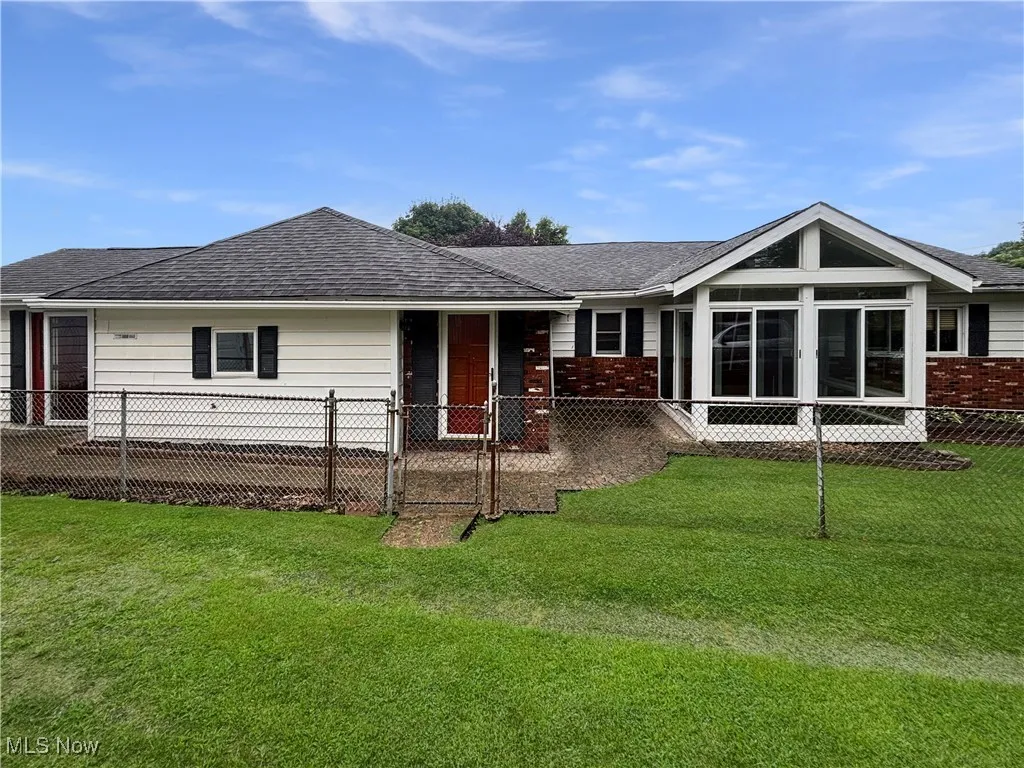 View of front of property with a shingled roof and a sunroom