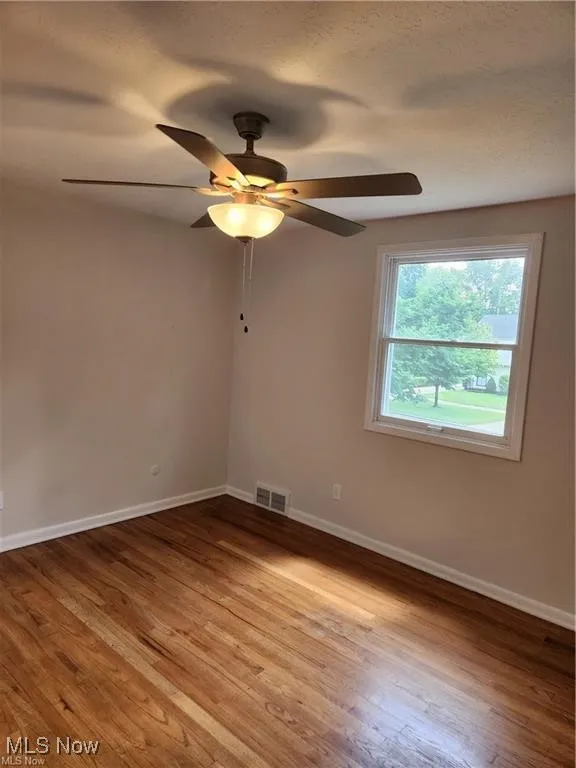 Unfurnished room with wood finished floors and a ceiling fan