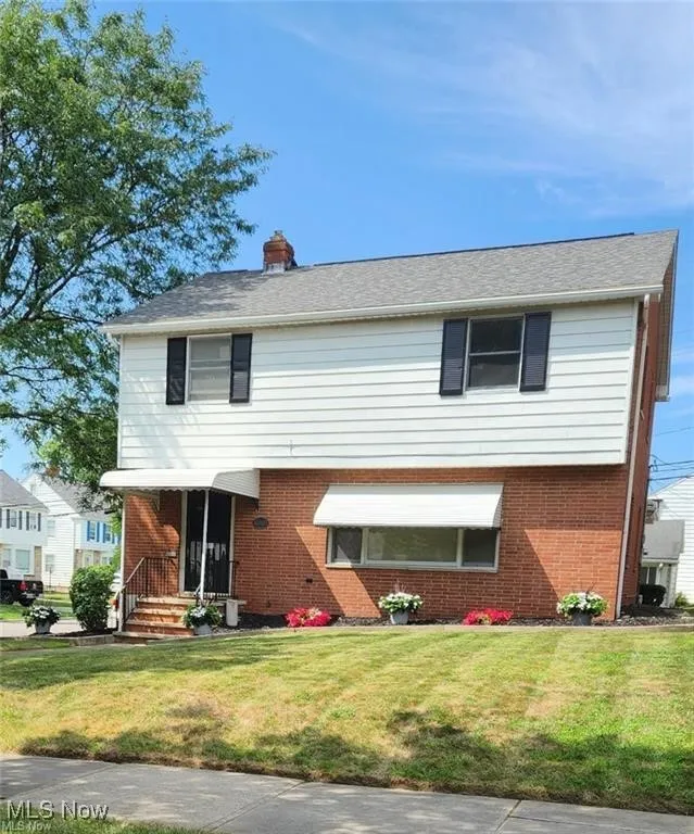 Colonial house featuring brick siding and a front lawn