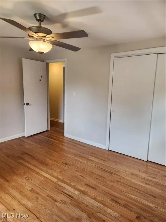 Unfurnished bedroom with light wood-style floors, a closet, and a ceiling fan