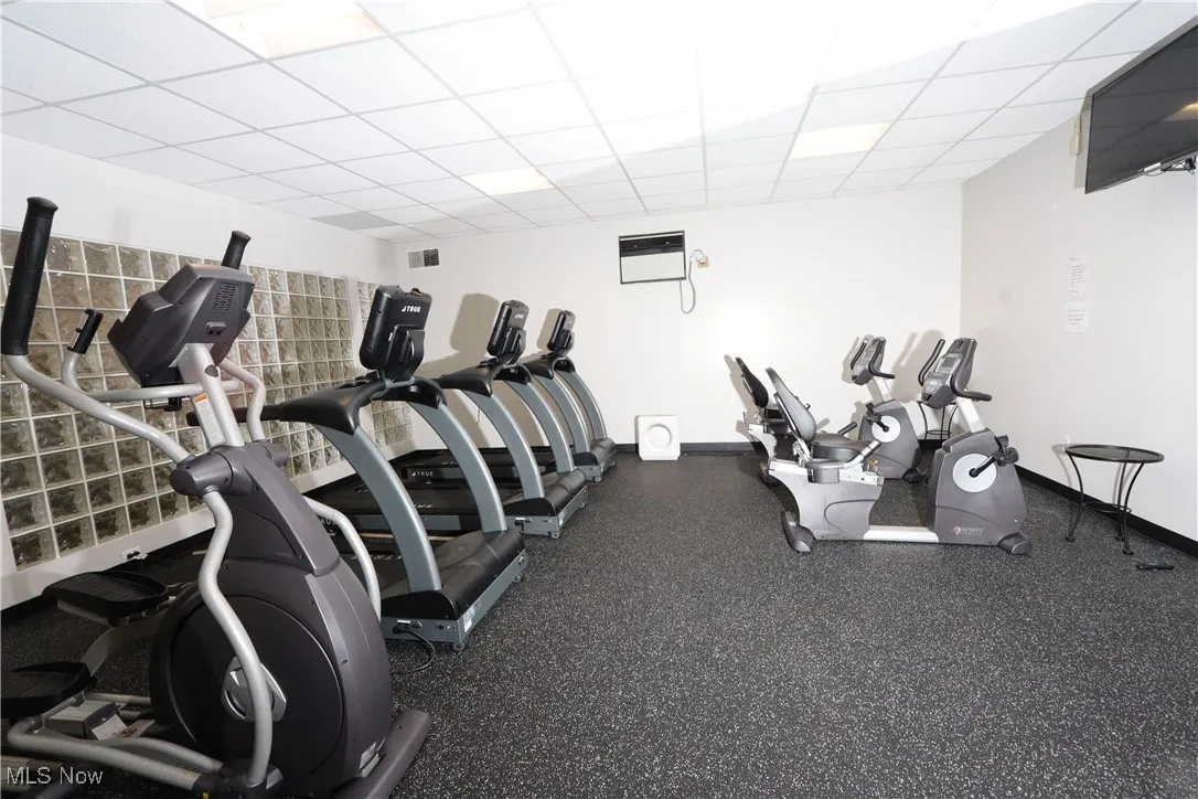 Gym featuring a drop ceiling and baseboards