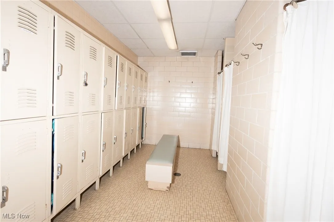 Hallway with tile walls, light tile patterned flooring, and a drop ceiling