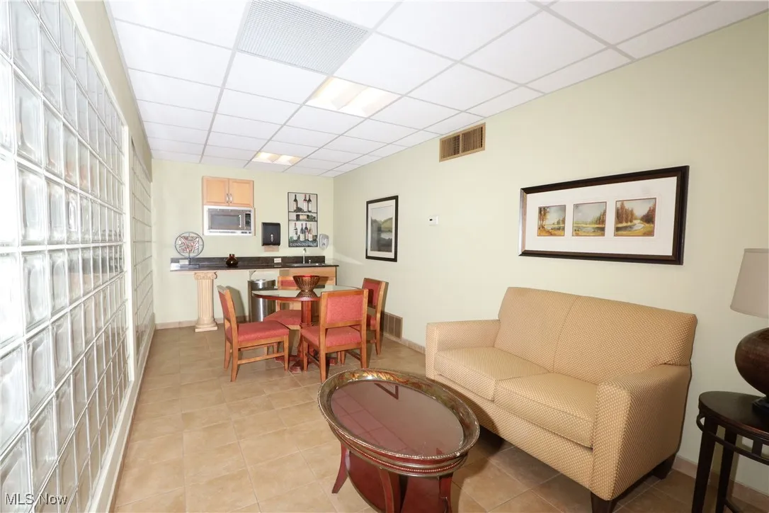 Living room featuring a paneled ceiling and light tile patterned floors