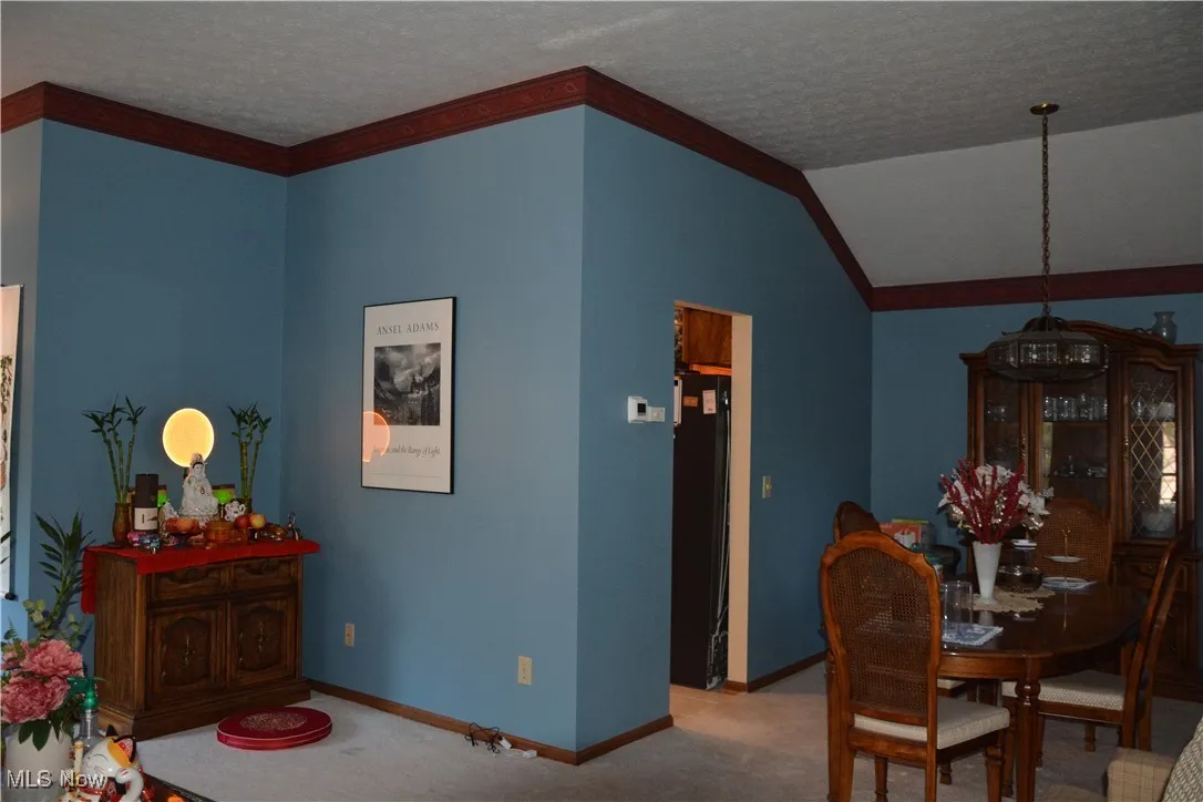 Carpeted dining area with a textured ceiling and vaulted ceiling