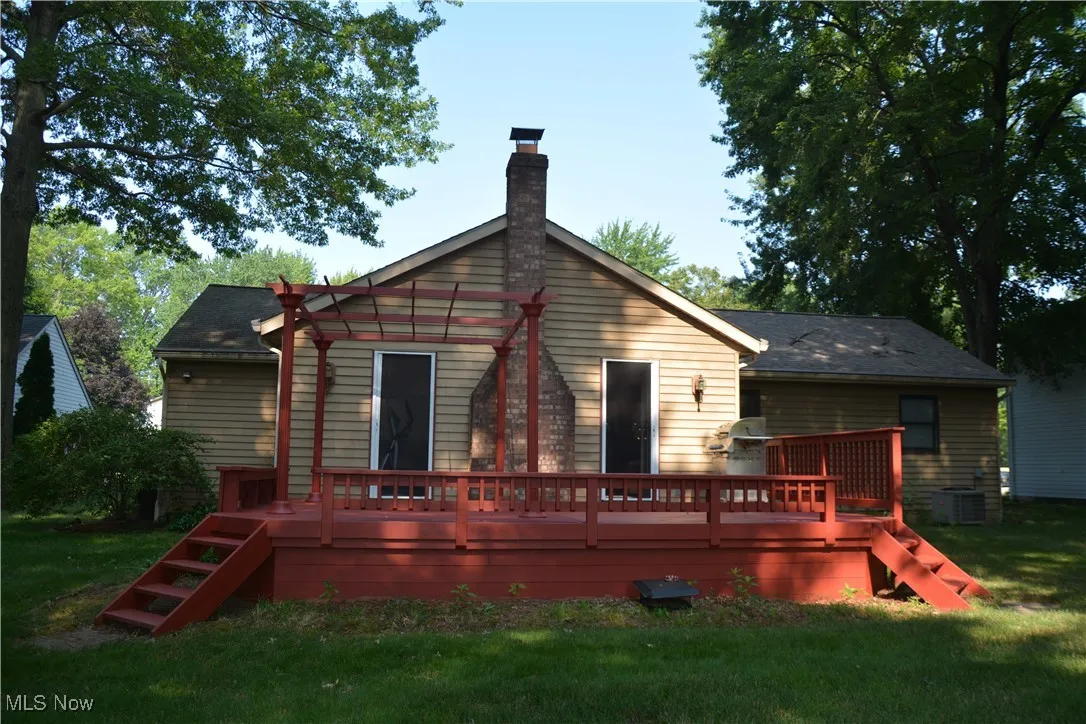 Rear view of house featuring a wooden deck, a chimney, and a yard