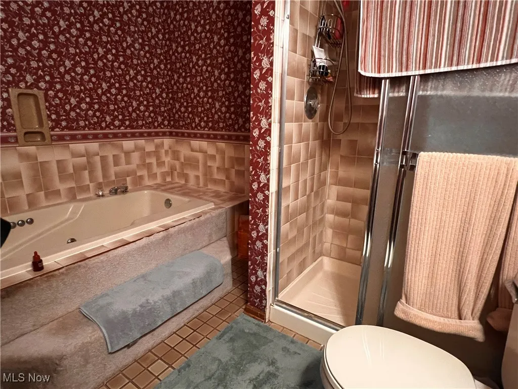 Full bathroom with wallpapered walls, a shower stall, a bath, and tile patterned flooring