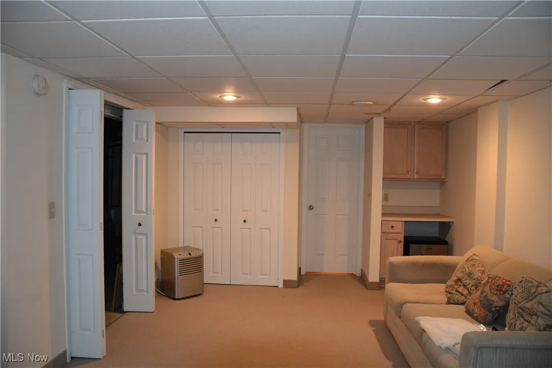Lower level Living area with light colored carpet, a drop ceiling, and recessed lighting
