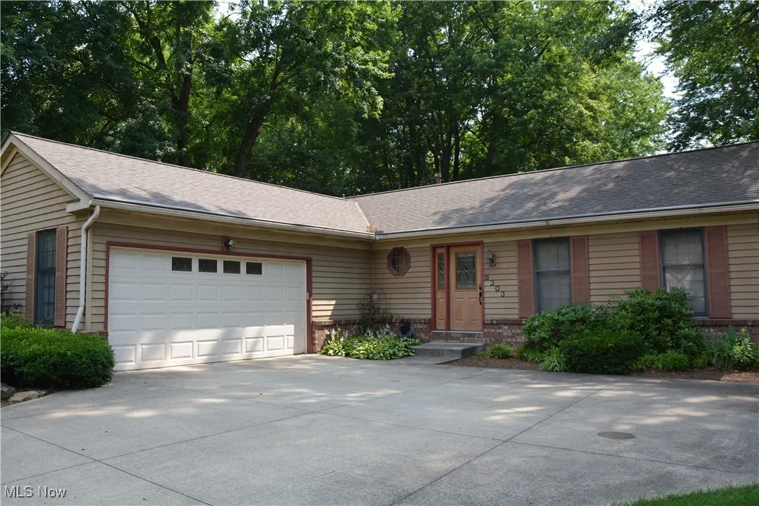 Ranch-style house with a garage, concrete driveway, brick siding, and a shingled roof