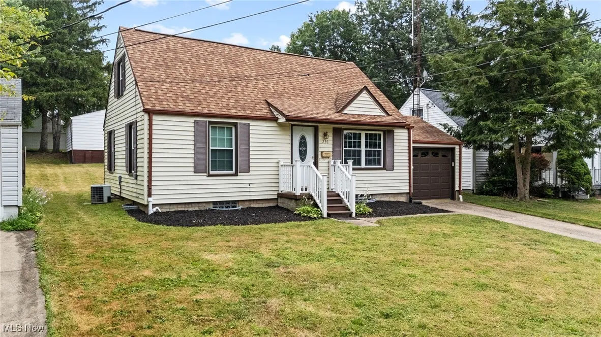 View of front of property with concrete driveway, roof with shingles approx 5-6 yrs old, an attached garage, and a front yard