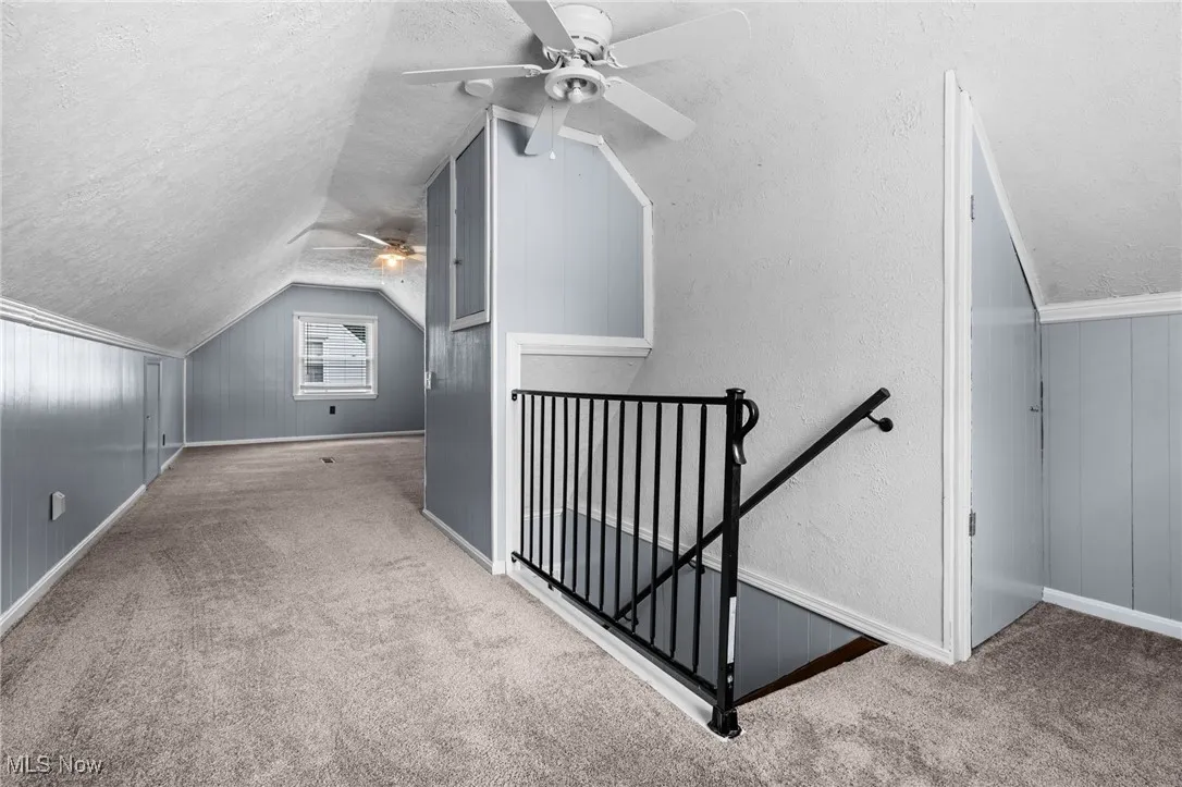 Upstairs bedroom #3 with 2 ceiling fans, carpet flooring, lofted ceiling, and a lots of storage closets
