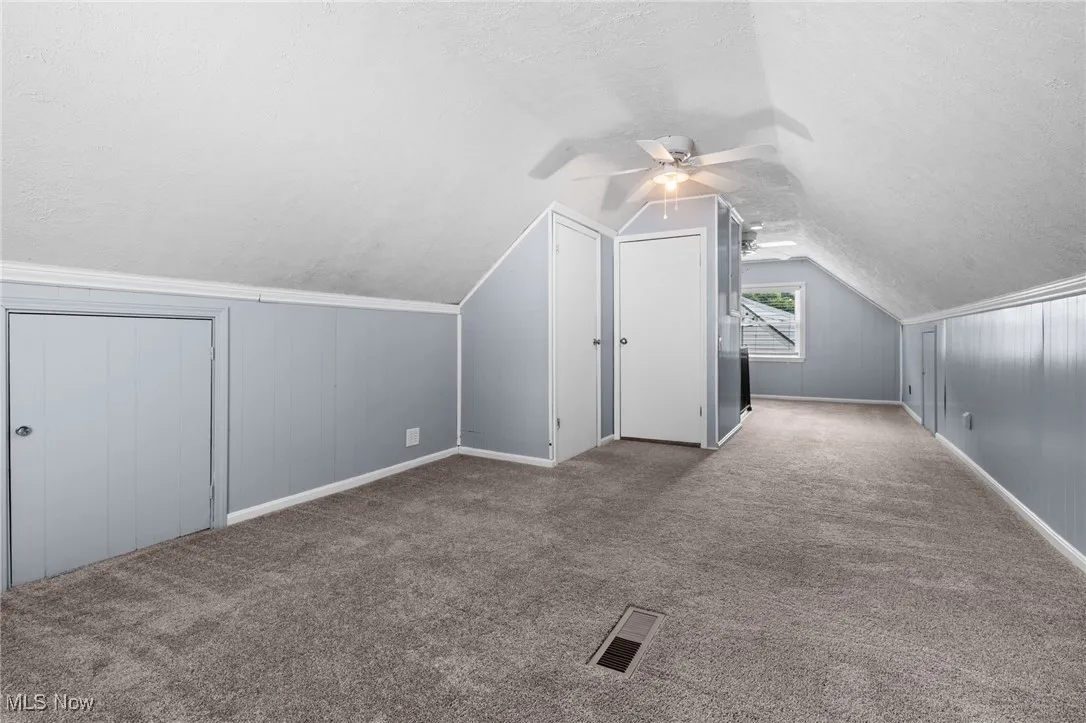 Upstairs bedroom #3 featuring a textured ceiling, 2 ceiling fans, carpet floors, and several storage closets