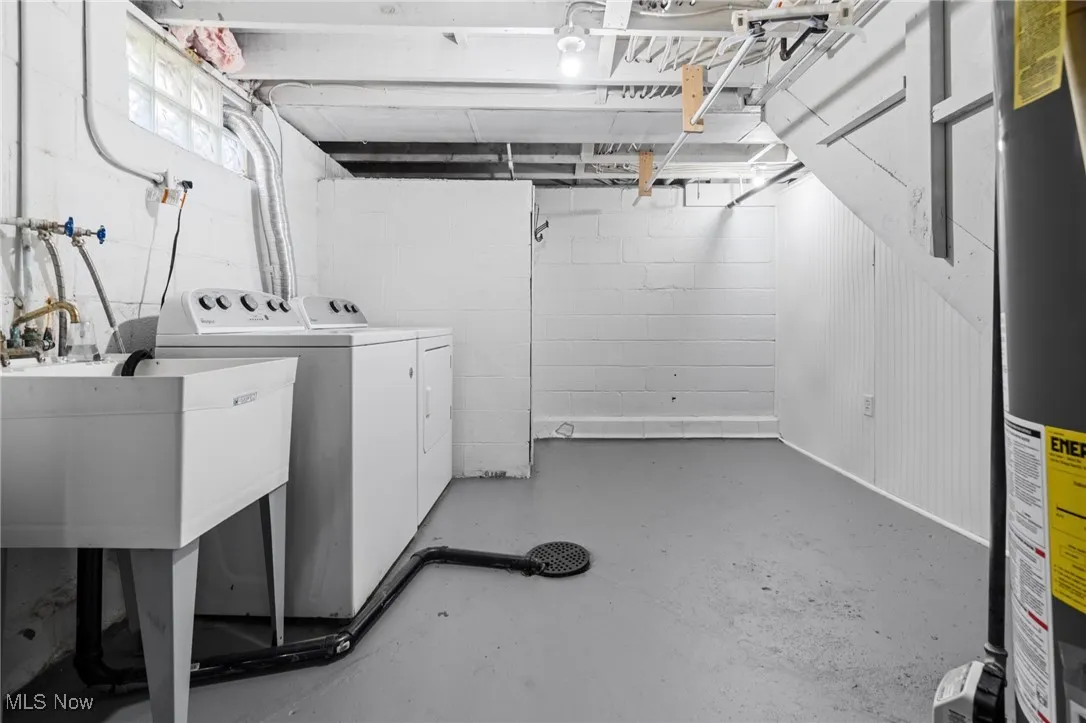 Basement with washing machine and dryer, gas water heater, utility sink and concrete block wall