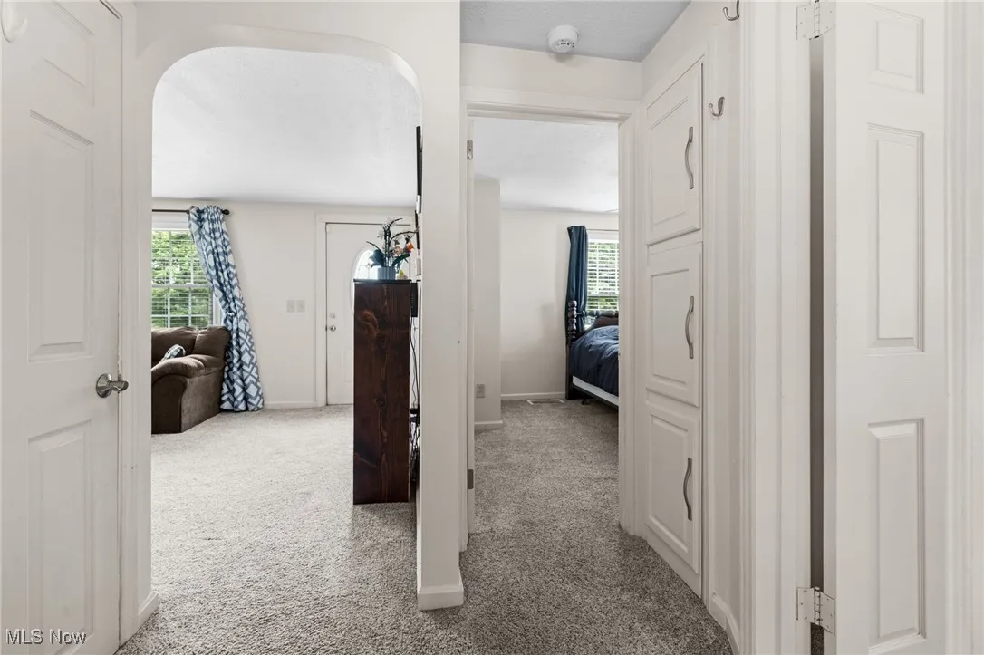 Hallway featuring carpet floors and arched doorway