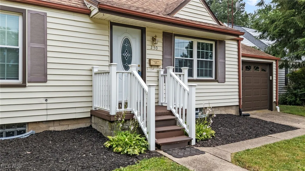 View of exterior entry with landscaped yard & attached mailbox