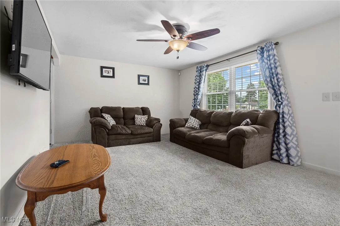 Carpeted living area with ceiling fan