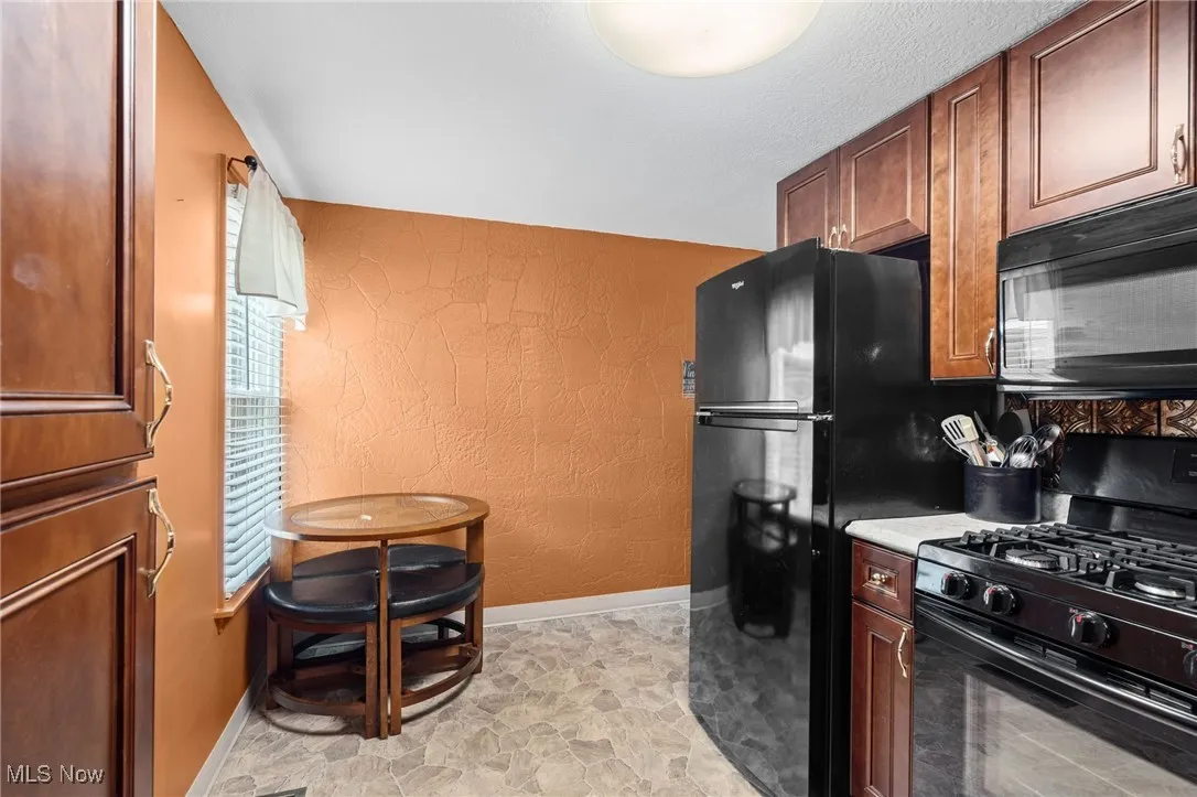 eat in Kitchen featuring black appliances, light countertops, and backsplash