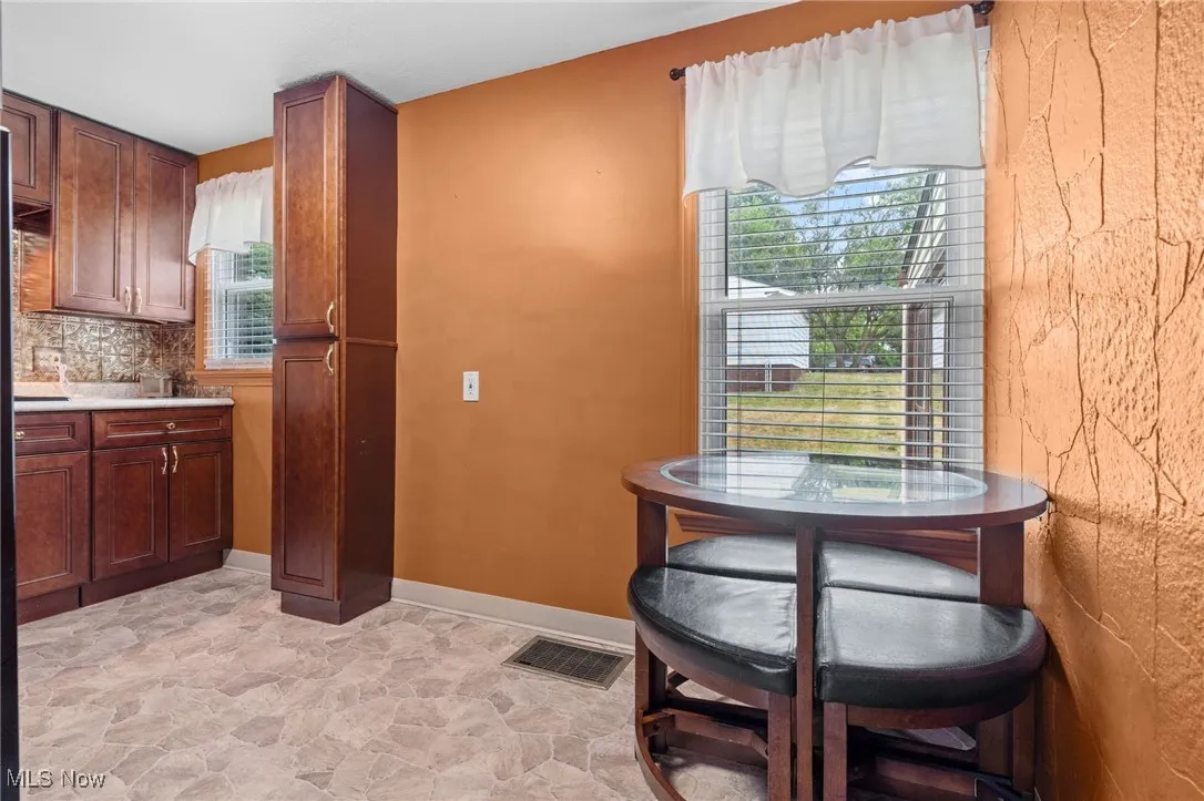 Kitchen with healthy amount of natural light, light vinyl flooring, light countertops, and tasteful backsplash