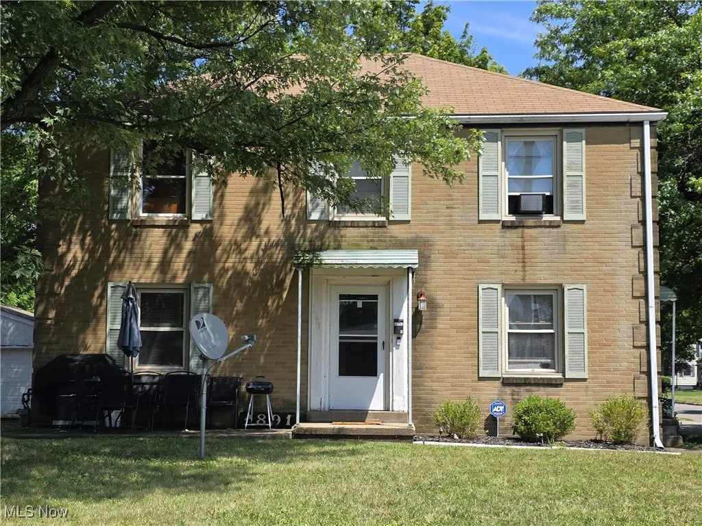 Colonial home with a front lawn and brick siding