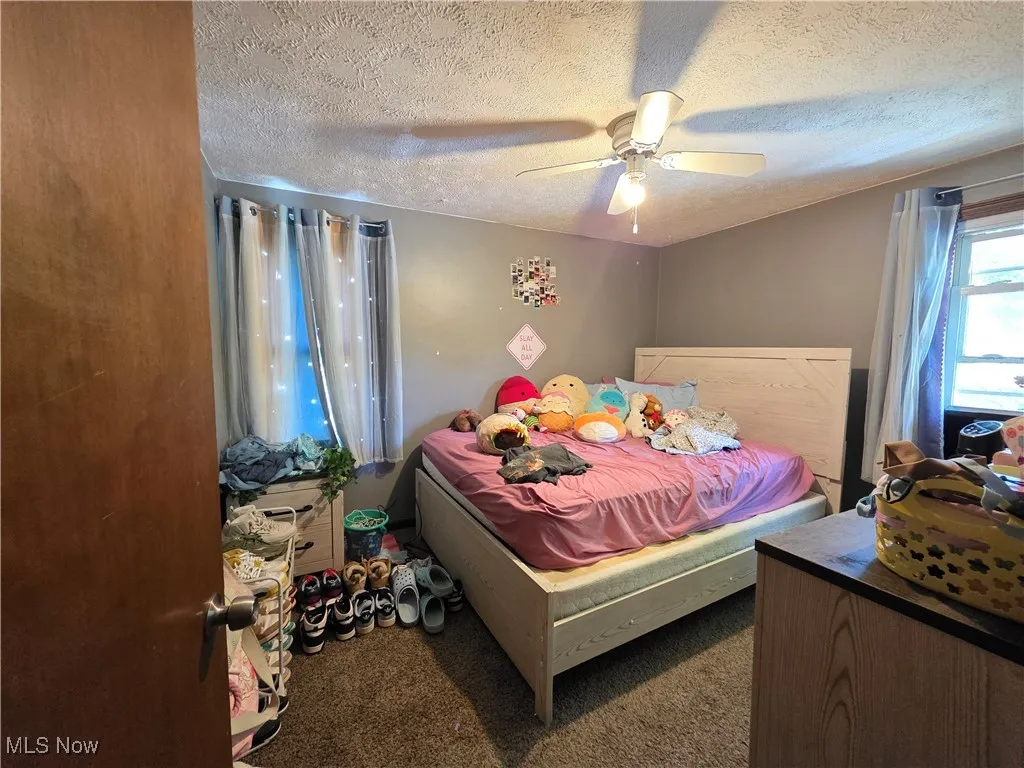 Bedroom featuring carpet, a textured ceiling, and ceiling fan